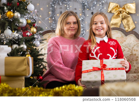 Mom and daughter holding gift in Christmas interior Mom and daughter holding gift in Christmas interior 118060508