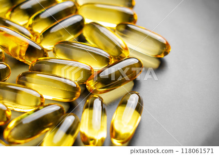Omega 3 supplements in golden translucent natural softgel capsules for energy and well-being on a grey ceramic plate. Macro shot Omega 3 supplements in golden translucent natural softgel capsules for energy and well-being on a grey ceramic plate. Macro shot 118061571