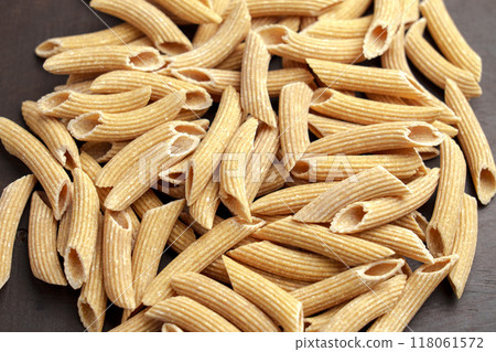 Dry penne pasta with gluten free quinoa ingredients on a wooden surface. Macro shot 118061572