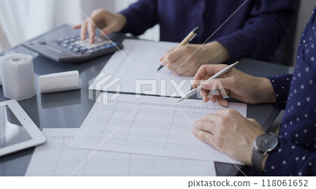 Two unrecognizable female accountants or auditors are sitting and reviewing financial documents in office. Audit and taxes 118061652