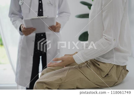 Doctor and a patient discussing something. The female physician, wearing a white medical coat standing with a clipboard during a consultation in the clinic, close up. Medicine concept 118061749