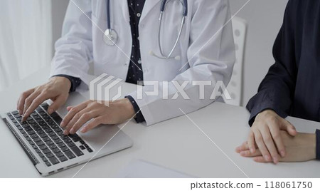 Doctor and a patient in clinic. The female physician is using laptop computer for filling up medication history record form, close up. Medicine and science 118061750