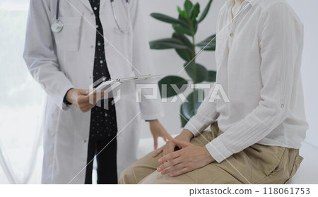 Doctor and a patient discussing something. The female physician, wearing a white medical coat standing with a clipboard during a consultation in the clinic, close up. Medicine concept Doctor and a patient discussing something. The female physician, wearing a white medical coat standing with a clipboard during a consultation in the clinic, close up. Medicine concept 118061753