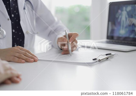 Doctor and a patient are discussing something at the desk near the laptop computer, close up of unrecognizable people's hands. Medicine concept Doctor and a patient are discussing something at the desk near the laptop computer, close up of unrecognizable people's hands. Medicine concept 118061784