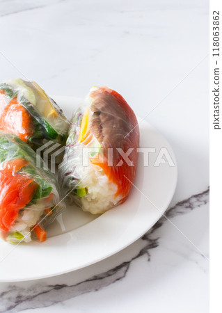 These traditional Vietnamese spring rolls feature rice paper filled with lettuce, salmon, carrots, and cucumber, served with fish sauce, offering a light and flavorful appetizer These traditional Vietnamese spring rolls feature rice paper filled with lettuce, salmon, carrots, and cucumber, served with fish sauce, offering a light and flavorful appetizer 118063862
