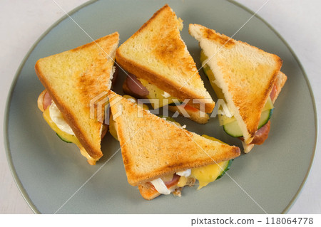 Cooked crispy hot sandwiches with sausage, cheese, vegetables on plate. 118064778