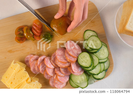 Woman cooking, hands cutting tomatoes on slices on wooden board. Woman cooking, hands cutting tomatoes on slices on wooden board. 118064794