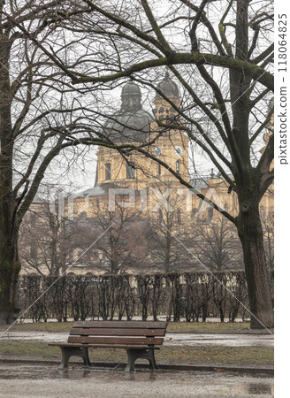 Bench made wood and iron stand in the garden of the Munich Residenz with St.Cajetan and Adelaide in the background. 118064825