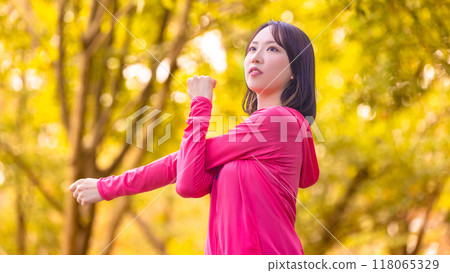 年輕女子在運動中在秋葉中伸展身體 年輕女子在運動中在秋葉中伸展身體 118065329