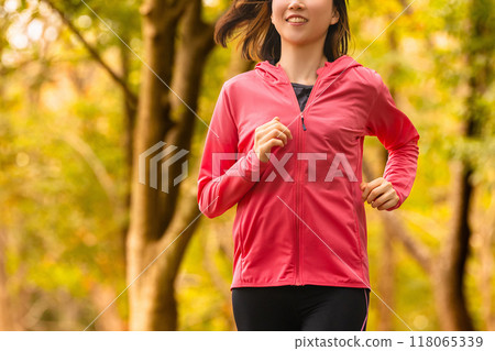 Sports autumn - Young woman jogging among autumn leaves 118065339