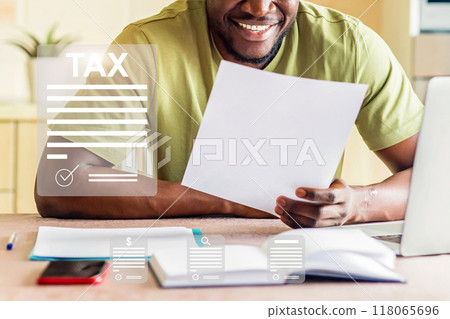 A man is sitting at a desk with a laptop and a stack of papers A man is sitting at a desk with a laptop and a stack of papers 118065696