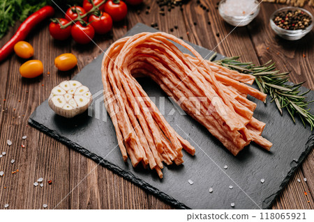 Light meat sticks on board with fresh herbs, garlic, and tomatoes, perfect for food styling needs Light meat sticks on board with fresh herbs, garlic, and tomatoes, perfect for food styling needs 118065921