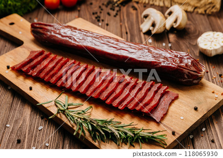 Sliced gourmet smoked salami on a wooden board with herbs, perfect for charcuterie boards and snacks Sliced gourmet smoked salami on a wooden board with herbs, perfect for charcuterie boards and snacks 118065930