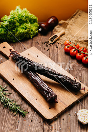Smoked salami sticks on a wooden board with herbs, perfect for charcuterie boards and gourmet snacks Smoked salami sticks on a wooden board with herbs, perfect for charcuterie boards and gourmet snacks 118065931