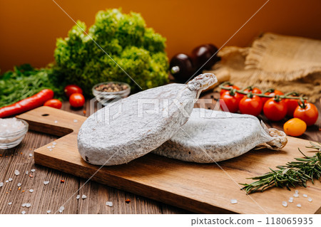 Dry-cured salami on board, ideal for rustic charcuterie presentations and gourmet food styling 118065935