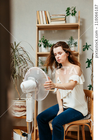 electric fan cools exhausted Caucasian woman languishing in summer heat electric fan cools exhausted Caucasian woman languishing in summer heat 118066187