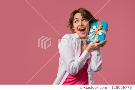 Happy woman with gift box on pink background. Lady smiling, interested what's inside. Copy space. Happy woman with gift box on pink background. Lady smiling, interested what's inside. Copy space. 118066776