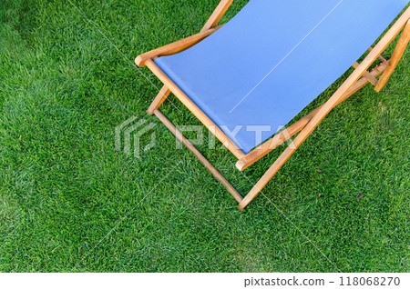 Deck chair with blue fabric on green grass background. 118068270