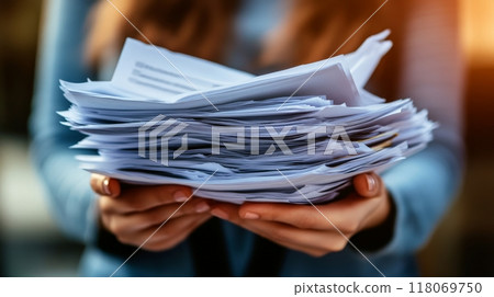 A person is gripping a substantial stack of documents, conveying a sense of urgency or completion in a relaxed environment during the late afternoon 118069750