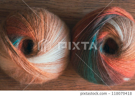 Two multi coloured yarn balls on table. Bright knitting yarn. Knitting hobby. Handicraft concept. Wool and alpaca wool threads. Autumn fashion. Needlework concept. Two multi coloured yarn balls on table. Bright knitting yarn. Knitting hobby. Handicraft concept. Wool and alpaca wool threads. Autumn fashion. Needlework concept. 118070418