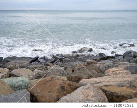resort in winter. The rocky shore is washed by the waves in cloudy weather. Black Sea coast. The coast of Batumi. Nature in shades of grey.  boring landscape 118071581