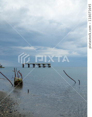 Reinforced concrete sticking out of the water. Remains of an old bridge in the sea. Ruined pier. Abandoned. Armature at sea. 118071645