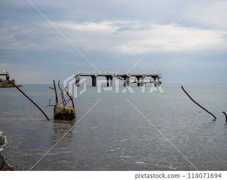 Reinforced concrete sticking out of the water. Remains of an old bridge in the sea. Ruined pier. Abandoned. Armature at sea. Reinforced concrete sticking out of the water. Remains of an old bridge in the sea. Ruined pier. Abandoned. Armature at sea. 118071694