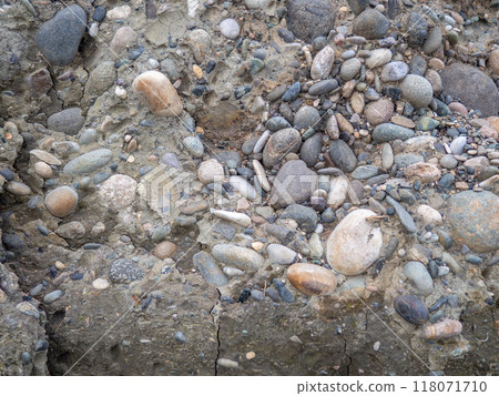Layers of earth on a beach made of pebbles. Soil cut. Cobblestones and earth. After the excavator. 118071710