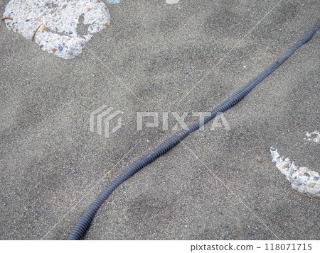 Cable on black sand. The cable sticks out of the ground. Electrical communications on the beach. Industry. Cable on black sand. The cable sticks out of the ground. Electrical communications on the beach. Industry. 118071715