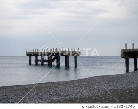 Reinforced concrete sticking out of the water. Remains of an old bridge in the sea. Ruined pier. Abandoned. Armature at sea. Reinforced concrete sticking out of the water. Remains of an old bridge in the sea. Ruined pier. Abandoned. Armature at sea. 118071740