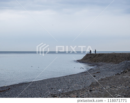 People walk along the coast. Cold season in the resort. Not a season. Gray landscape. 118071771