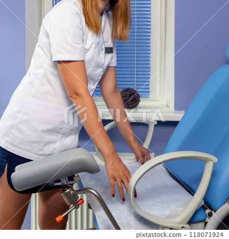 The nurse places a clean towel on the examination table 118071924