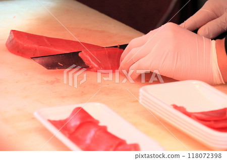 Cutting tuna for sashimi: A craftsman's hands cutting tuna Cutting tuna for sashimi: A craftsman's hands cutting tuna 118072398