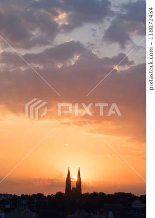 Morning sun rising among two church towers. Beautiful cozy sunrise over the city. 118072434