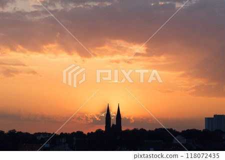 Morning sun rising among two church towers. Beautiful cozy sunrise over the city. Morning sun rising among two church towers. Beautiful cozy sunrise over the city. 118072435