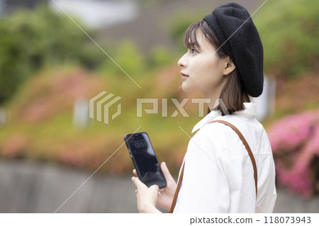 A woman sightseeing while looking at her smartphone A woman sightseeing while looking at her smartphone 118073943