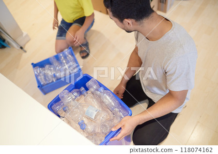 This is how to raise kids in a good way. Shot of a young man of and his child gathering bottles to recycle at home. This is how to raise kids in a good way. Shot of a young man of and his child gathering bottles to recycle at home. 118074162