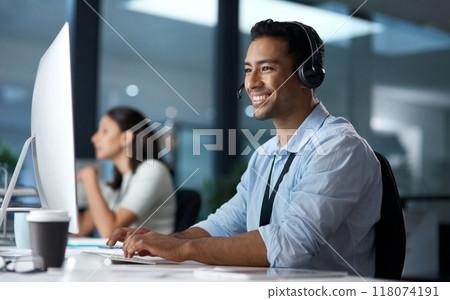 Courtesy and professionalism pays off. Shot of a young man using a headset and computer in a modern office. 118074191