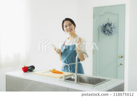 A woman in an apron cooking in the kitchen A woman in an apron cooking in the kitchen 118075012