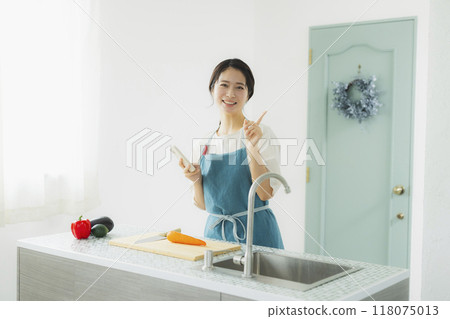 A woman in an apron cooking in the kitchen A woman in an apron cooking in the kitchen 118075013