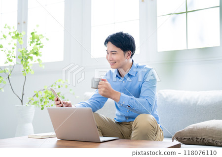 一名男子一邊看電腦一邊操作智慧型手機 118076110