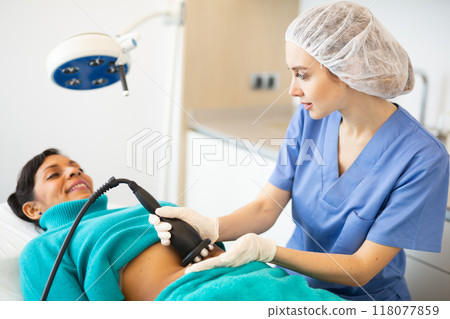 Doctor making rejuvenation electroporation procedure on abdomen 118077859