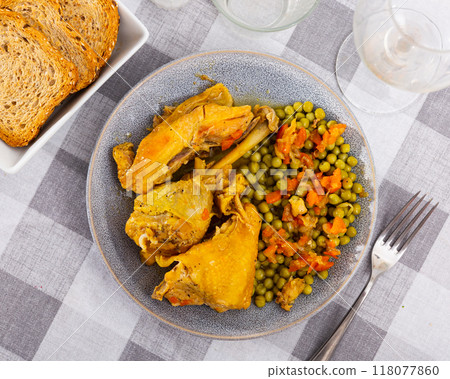 Hearty homemade lunch - few pieces of stewed chicken and green peas with carrots 118077860