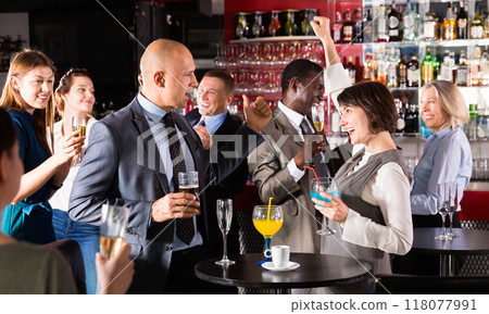 Cheerful male and female colleagues having fun on corporate party in bar Cheerful male and female colleagues having fun on corporate party in bar 118077991
