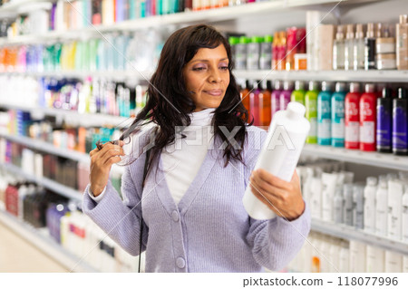 Adult Latina choosing haircare cosmetics in specialized boutique 118077996