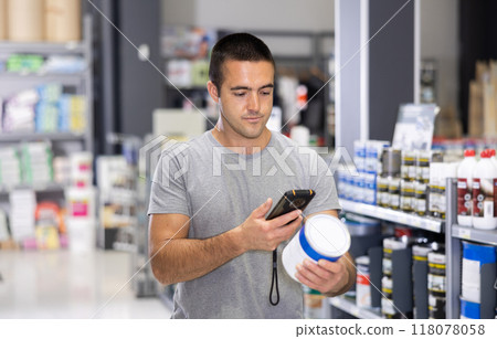 Man scanning barcode on paint can with smartphone in hardware store 118078058