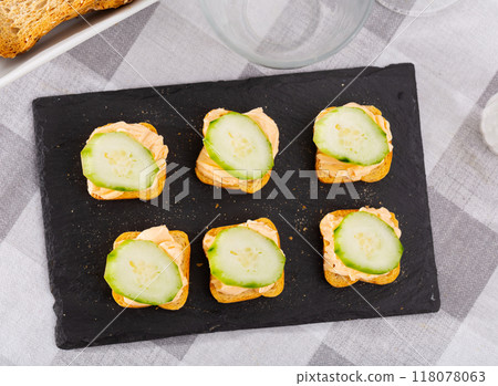 Simple homemade snack of sandwiches, greased with butter and decorated with slice of cucumber 118078063