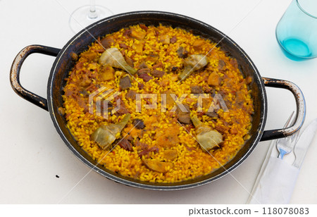 Delicious paella with meats and artichokes in traditional paellera Delicious paella with meats and artichokes in traditional paellera 118078083