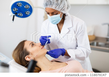 Woman cosmetician giving lip injections of botulinum toxin for young woman Woman cosmetician giving lip injections of botulinum toxin for young woman 118078147