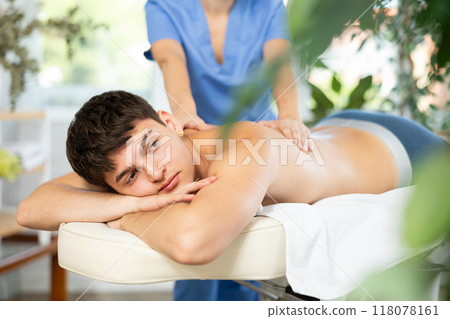 Female massagist doing massage to male client in spa center 118078161